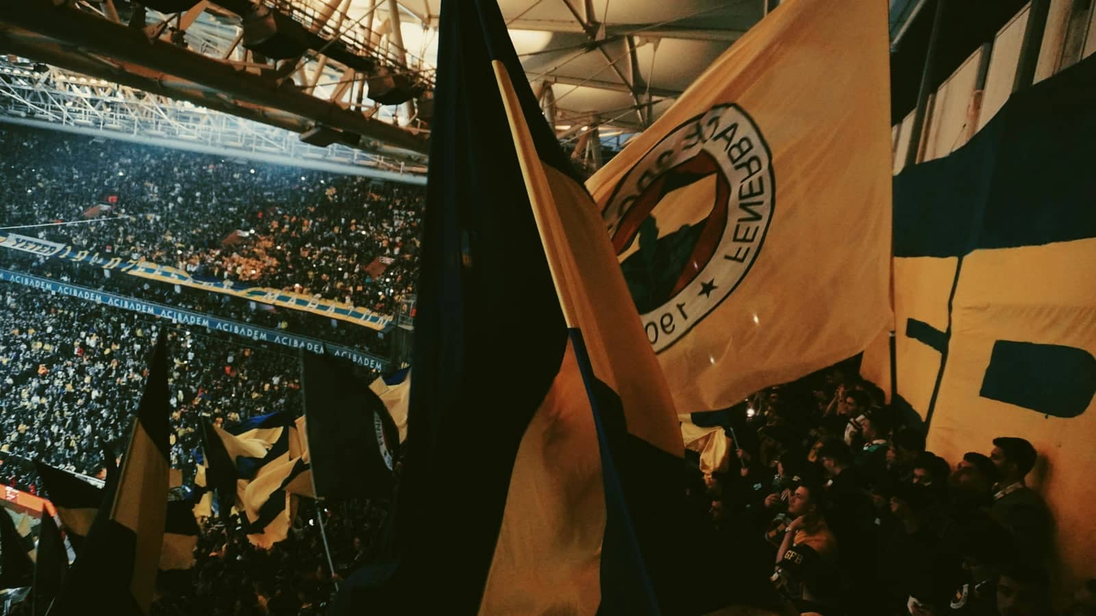Football fans waving flags at a stadium during a major tournament night