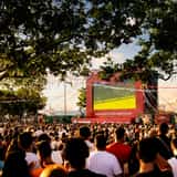 Fans gathered outdoors watching a football match on a giant public screen